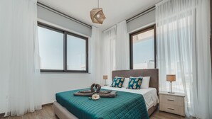Una camera da letto moderna con un letto grande, due finestre, un comodino e una lampada a sospensione.