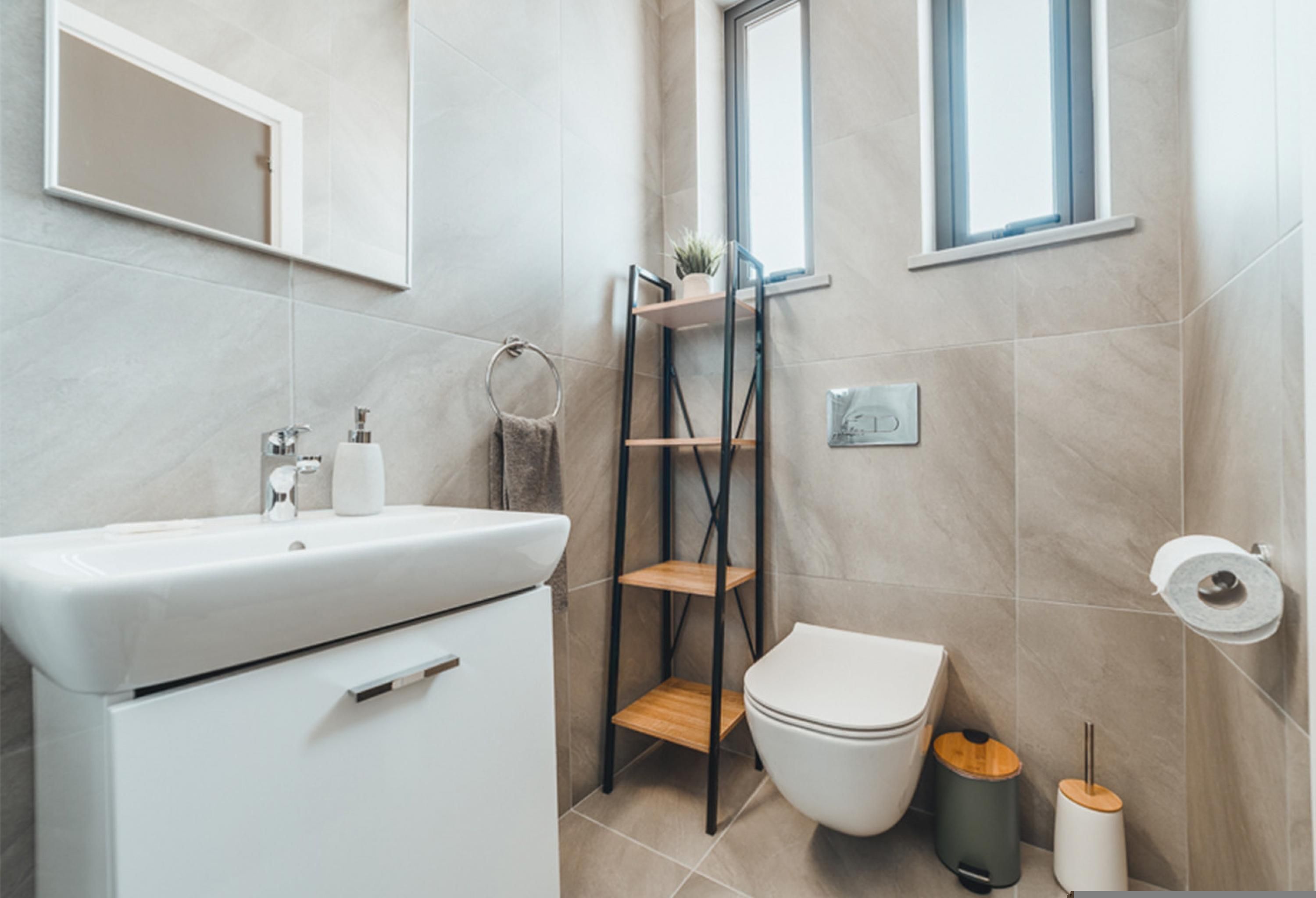 Een moderne badkamer met een wit wastafelmeubel, toilet en planken.