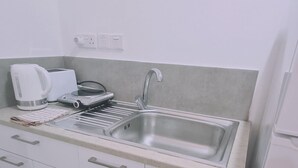 Eine Küche mit Spüle aus Edelstahl, einem Wasserkocher, einem Toaster und einem Geschirrtuch auf der Arbeitsfläche.