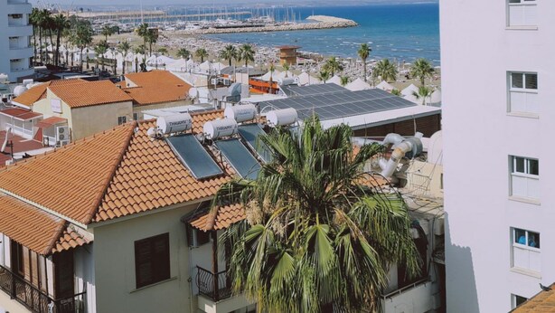 Uma área residencial costeira com edifícios, painéis solares e um porto de iates.