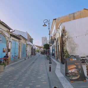 A narrow street lined with buildings, some with closed shutters. There is a sign for Big Bun, a restaurant, on the right. - 80 LCA - Stay Finikoudes Soul (Larnaca)