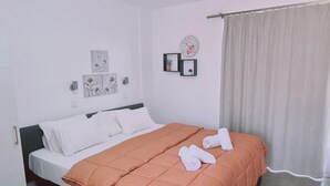 Un lit bien fait, avec une couette de couleur pêche, des oreillers blancs et deux serviettes enroulées posées sur le lit.