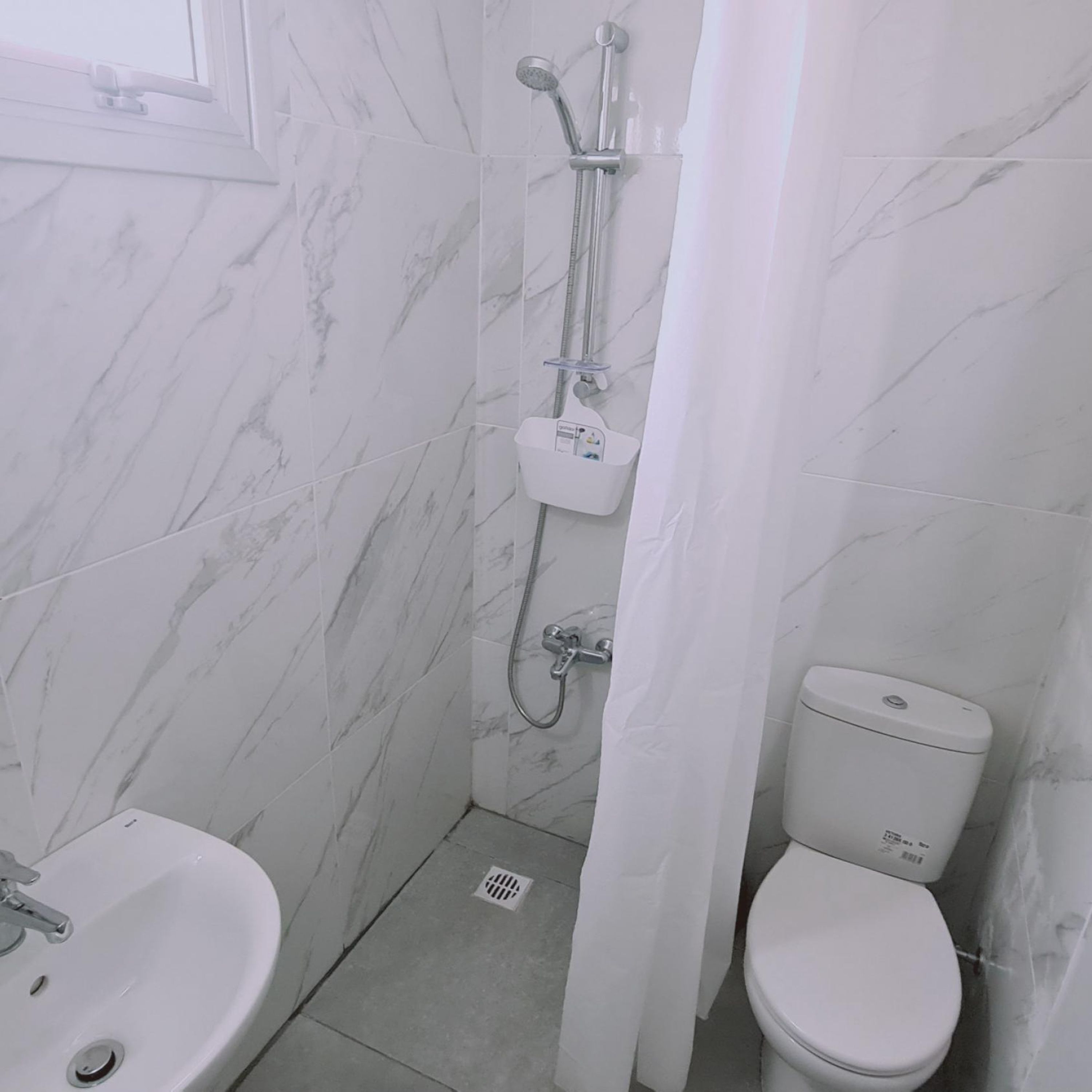 A bathroom with a white toilet, a sink, and a shower with a curtain.