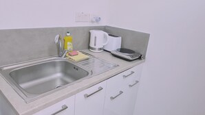 A kitchen with a stainless steel sink, a kettle, a toaster, and a scale. - 100 AN - Napa Living 19 (Ayia Napa)