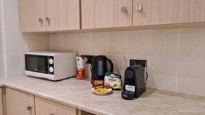 Eine Küche mit einer Mikrowelle, einer Kaffeemaschine und einer Mini-Kaffeemaschine auf der Arbeitsfläche.