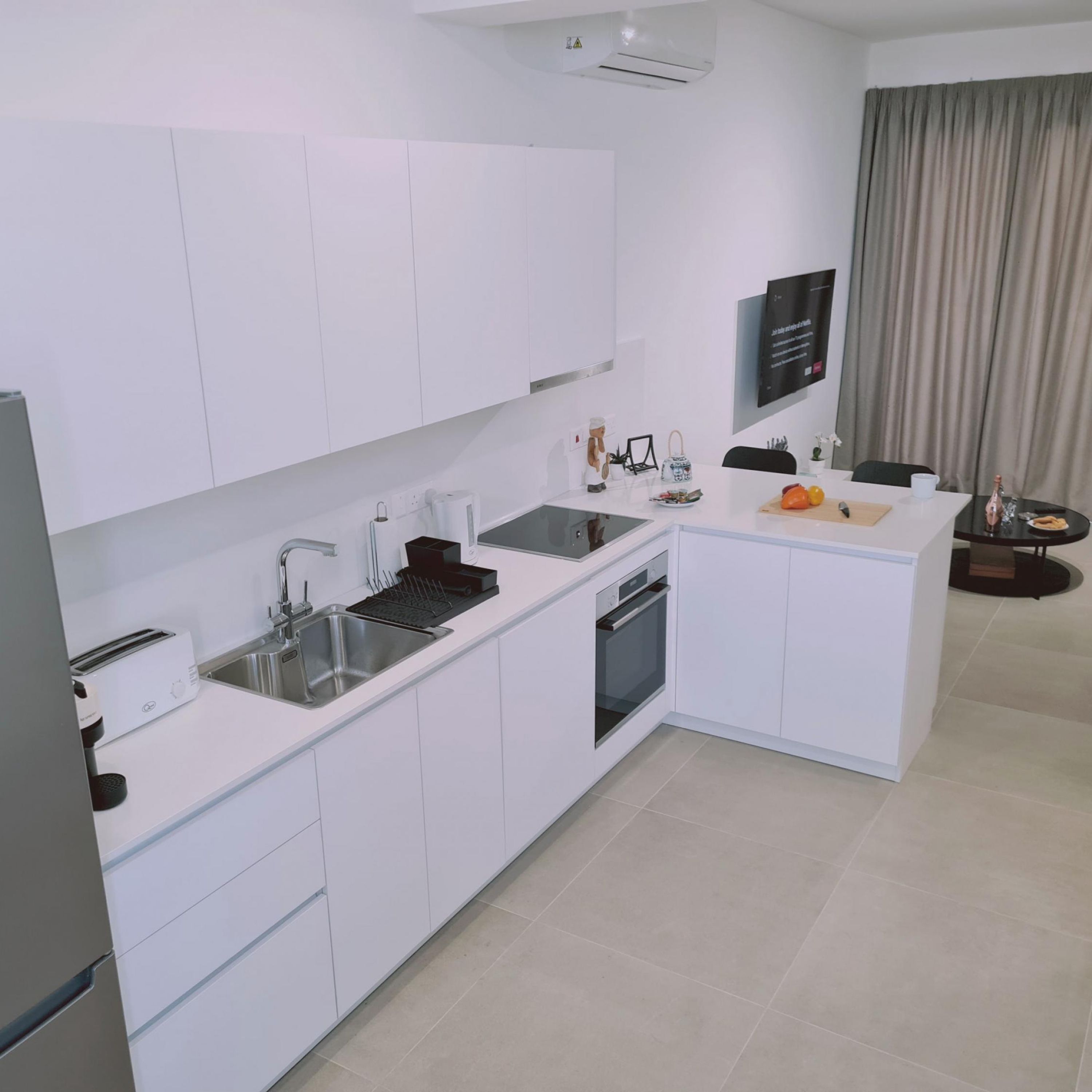 A modern kitchen with white cabinetry, a built-in oven, and a sink.