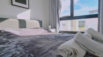Relax in this inviting room with a large bed, a framed picture, and a window offering a view of the surrounding buildings.