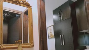 Una habitación con un aparador de madera, un espejo grande con marco decorativo y un armario oscuro con detalles plateados.