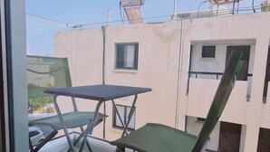 Un balcone con tavolo e due sedie, un edificio con una finestra e una porta, e un serbatoio d'acqua sul tetto.