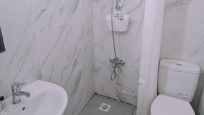 Un bagno con lavandino, water e doccia, tutti in bianco.
