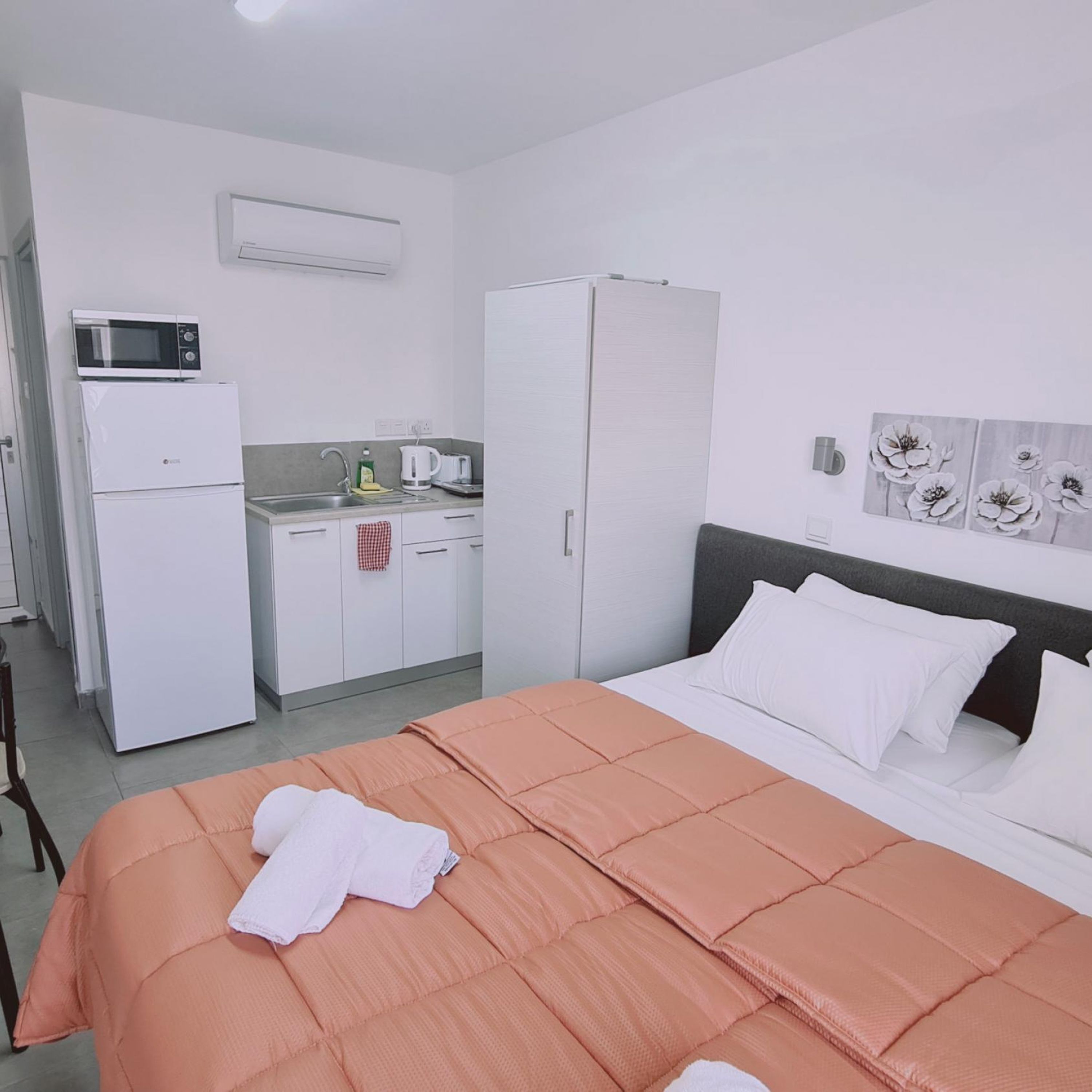 Een hotelkamer met een bed, een kitchenette en een kledingkast.