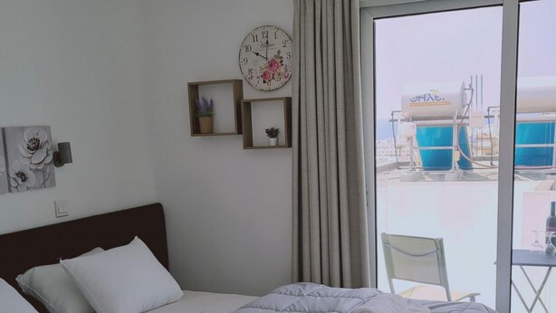 Ein Hotelzimmer mit Bett, einer Uhr und Blick auf einen Poolbereich.
