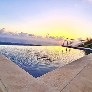 A swimming pool with a view of the sunset over the water. - 95 1 TLA - Stay Sunset Grand Palazzo (Tala)