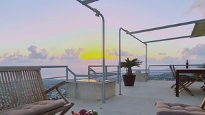 A terrace with a table set for dining, a potted plant, and a view of the sea at sunset. - 95 1 TLA - Stay Sunset Grand Palazzo (Tala)