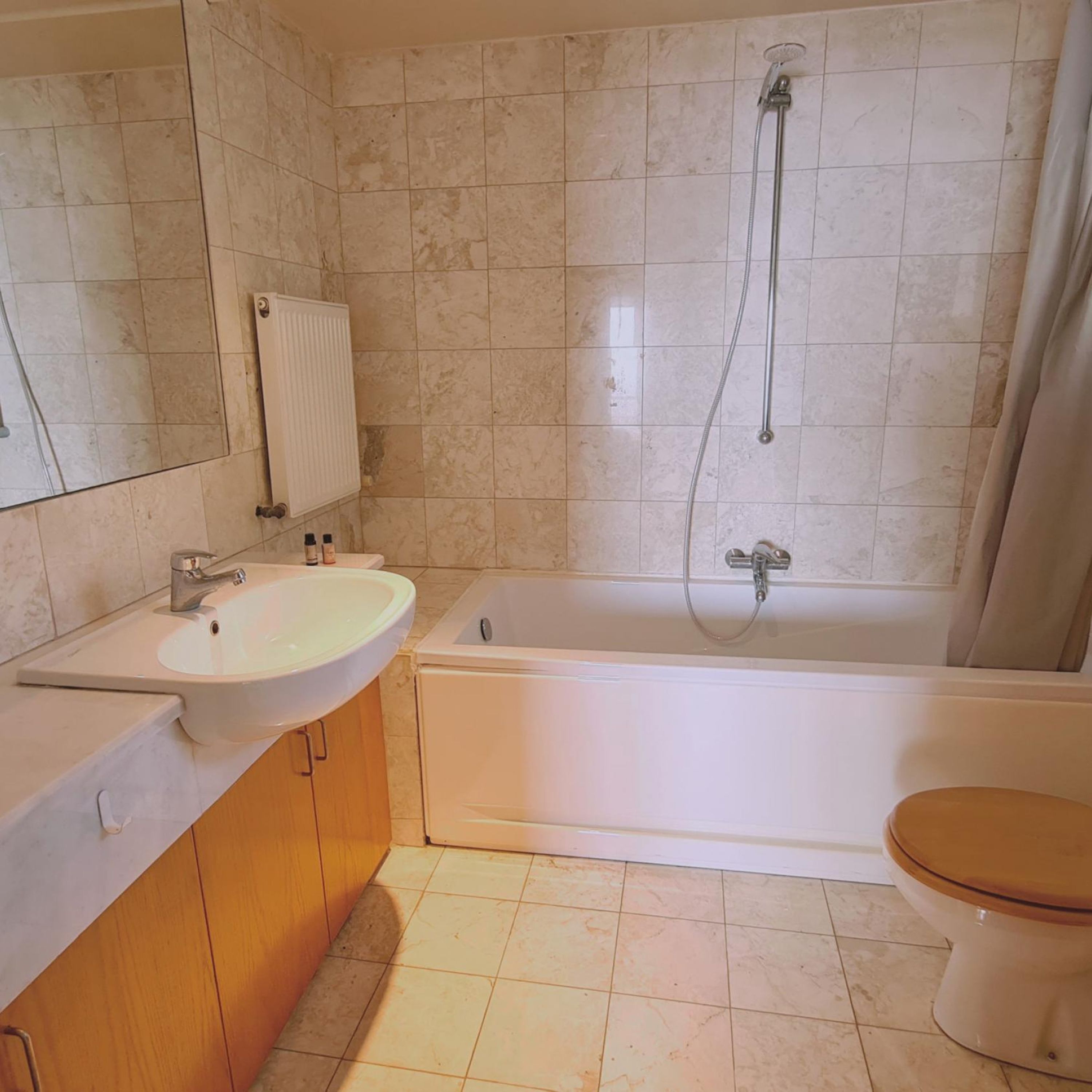 A bathroom with a sink, mirror, toilet, and bathtub.