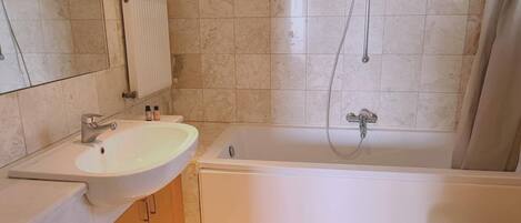A bathroom with a sink, mirror, toilet, and bathtub.
