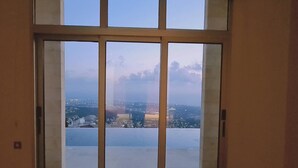 A room with a large sliding glass door leading to a city view. - 95 1 TLA - Stay Sunset Grand Palazzo (Tala)