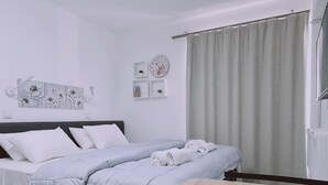 Une chambre d’hôtel moderne avec un lit, une petite table sur laquelle sont disposés des fruits, et une vue sur la ville par la fenêtre.