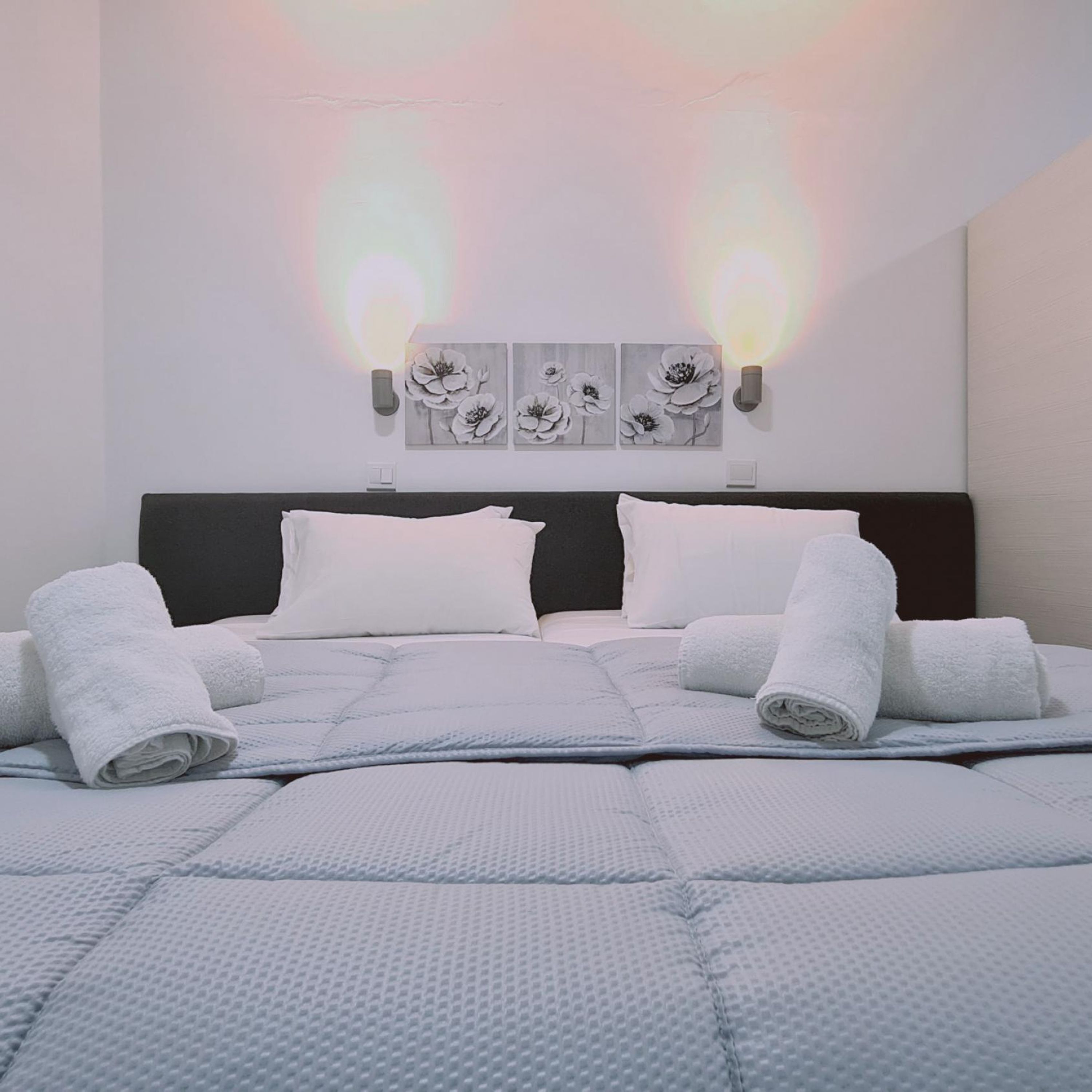 Een netjes opgemaakt bed met witte handdoeken, een hoofdbord en wanddecoratie.