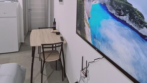 A dining area with a table, chairs, and a large TV screen displaying a coastal scene.