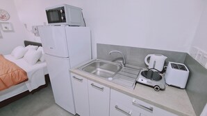 Eine kleine Küchenzeile mit Kühlschrank, Mikrowelle, Spüle, Wasserkocher und Toaster.