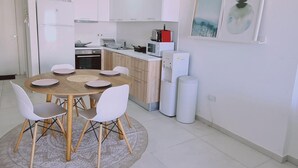 A modern kitchen with white cabinets, a dining table with chairs, and a microwave. - 78 LCA - Stay Kallucci s Maison de la mer (Larnaca)