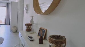 A modern interior with a white console table, a large mirror, a small bird figurine, a picture frame, a vase, and a decorative jar. - 78 LCA - Stay Kallucci s Maison de la mer (Larnaca)