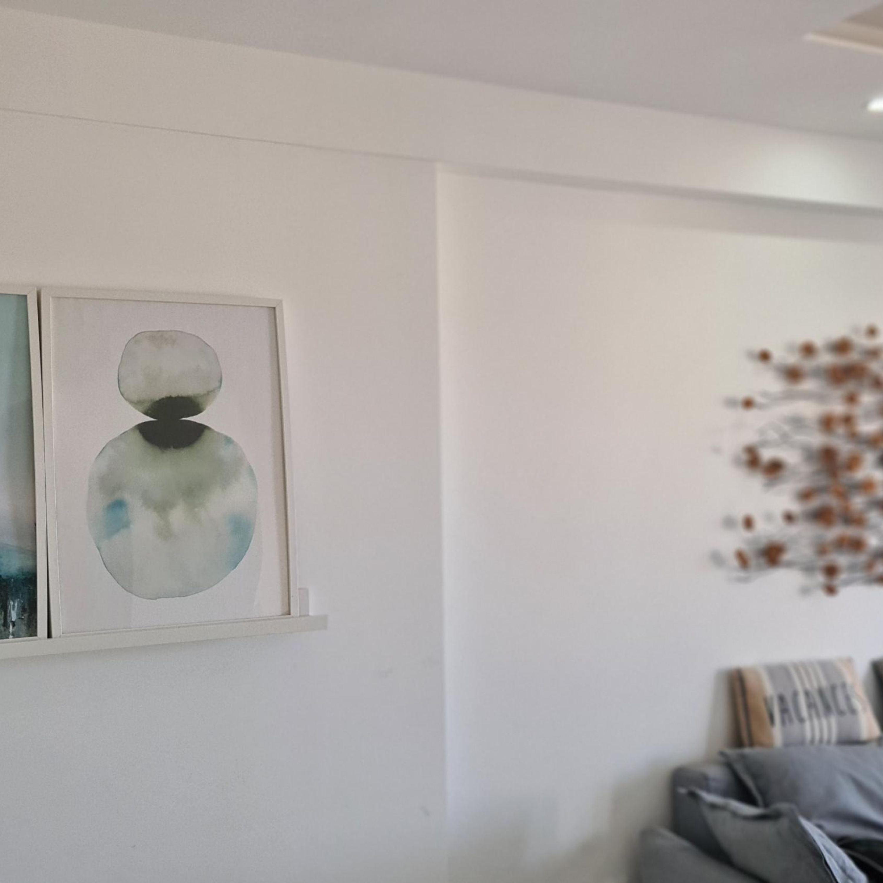 Une pièce avec un mur blanc, un tableau abstrait encadré et un élément décoratif mural.