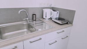 Una cocina moderna con un lavamanos de acero inoxidable, una cafetera, un tostador y una balanza.