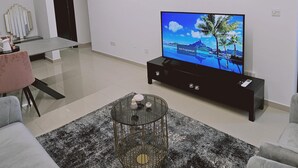 A modern living room with a flat-screen TV, a glass coffee table, and a black sofa. - 104 NIC - 403 Stay Cosmo City Suite (Nicosia)