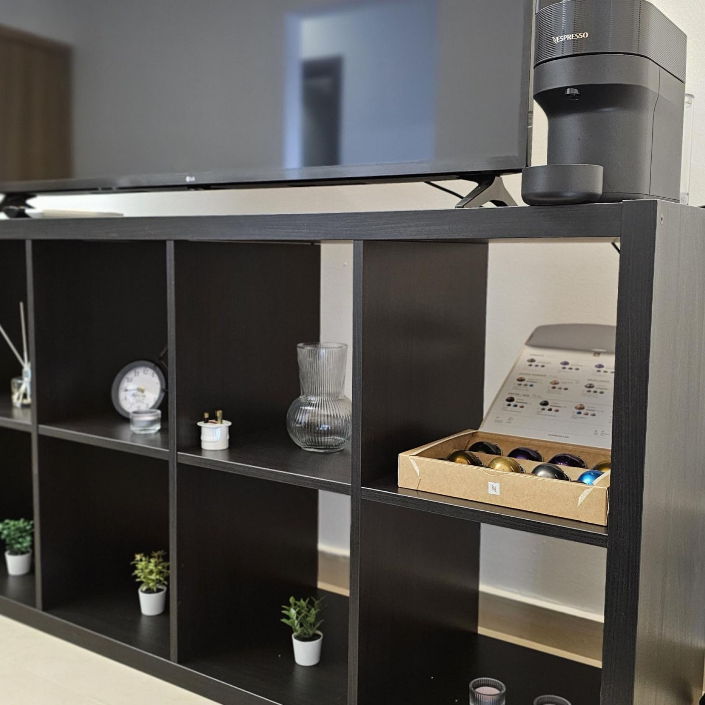 A black shelving unit with various items including a clock, a vase, and a box of items.