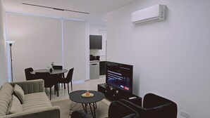 Un salon moderne comprenant un canapé, une table basse, un téléviseur et un coin repas avec des chaises et une table.