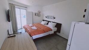 Ein Hotelzimmer mit Bett, Schreibtisch, Fernseher und Kühlschrank.
