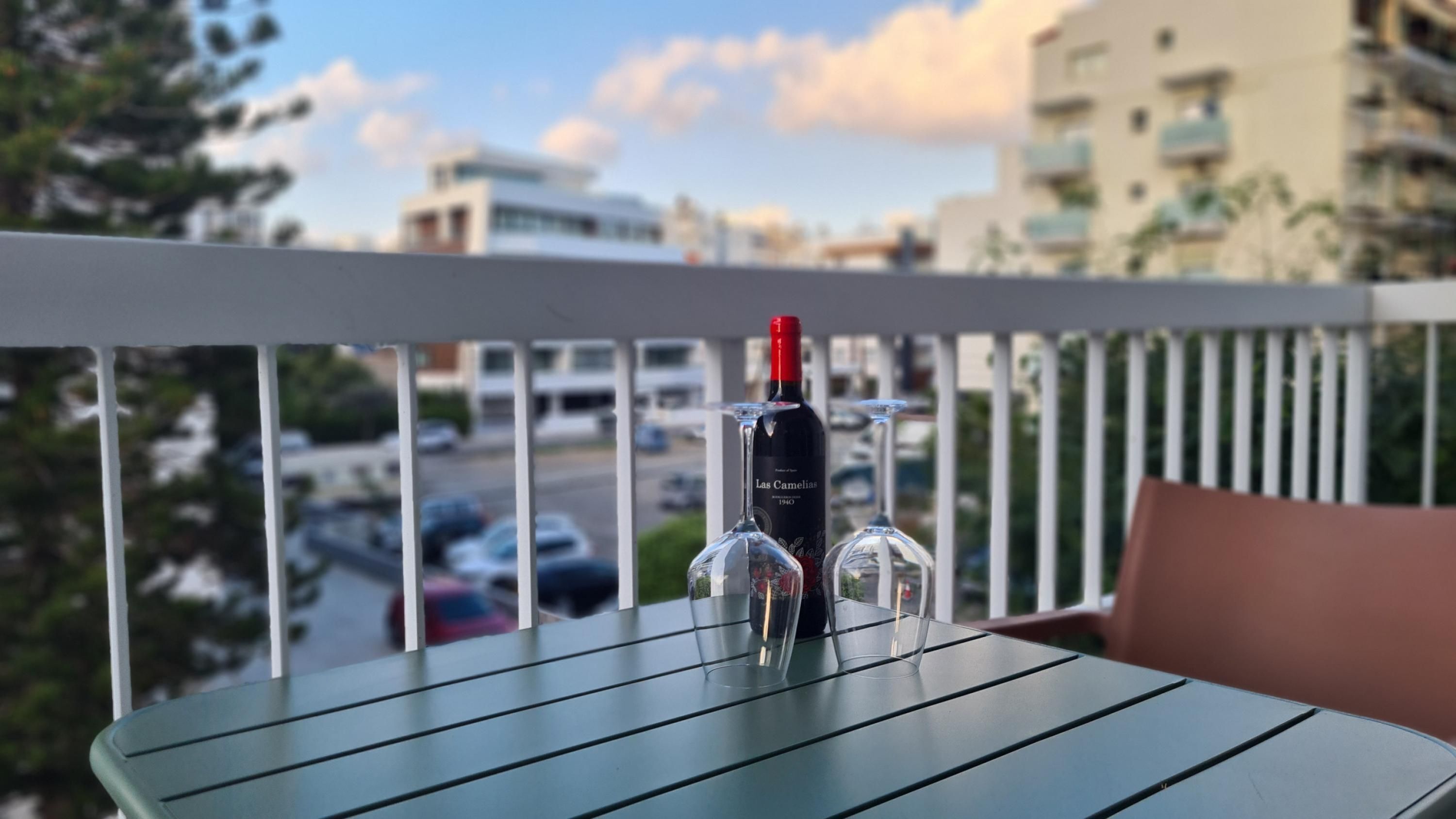 Un balcon avec une table, une bouteille de vin et deux verres à vin.
