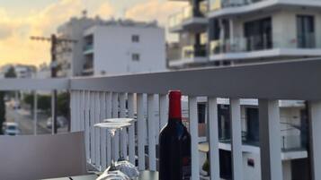A balcony with a table, a bottle of wine, and two glasses.