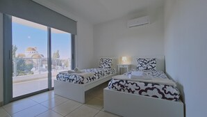 Ένα δωμάτιο ξενοδοχείου με δύο κρεβάτια, ένα μεγάλο παράθυρο και θέα σε ένα κτίριο με θόλους.