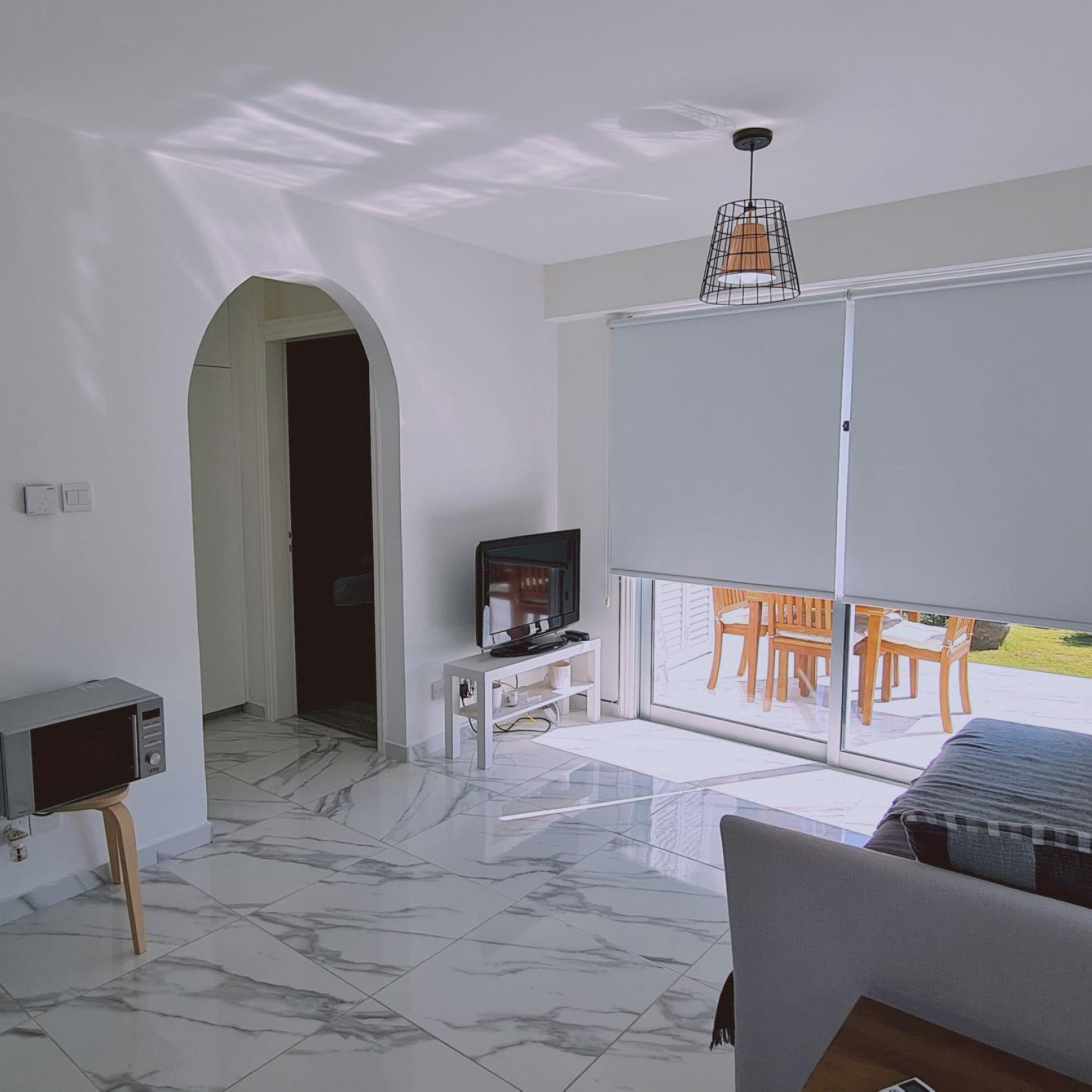 A modern living room with a television, a sofa, and a balcony with outdoor furniture.