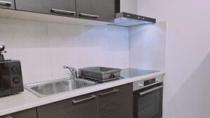 Una cuina moderna amb armaris foscos, una aixeta d'acer inoxidable, un forn integrat i un microones.