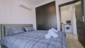 Un dormitori amb llit, armari i rentadora.
