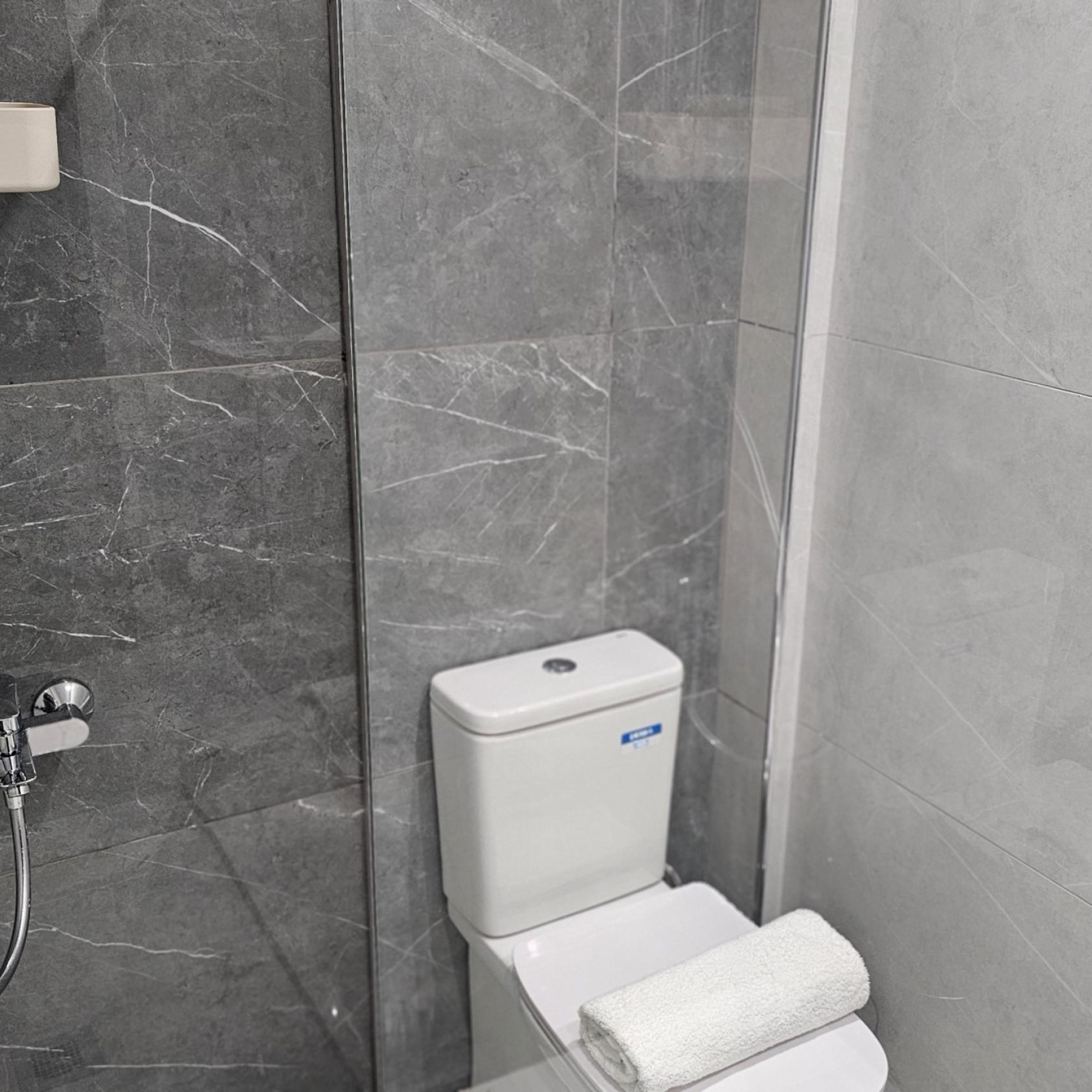 A bathroom with a toilet, a towel, and a shower.