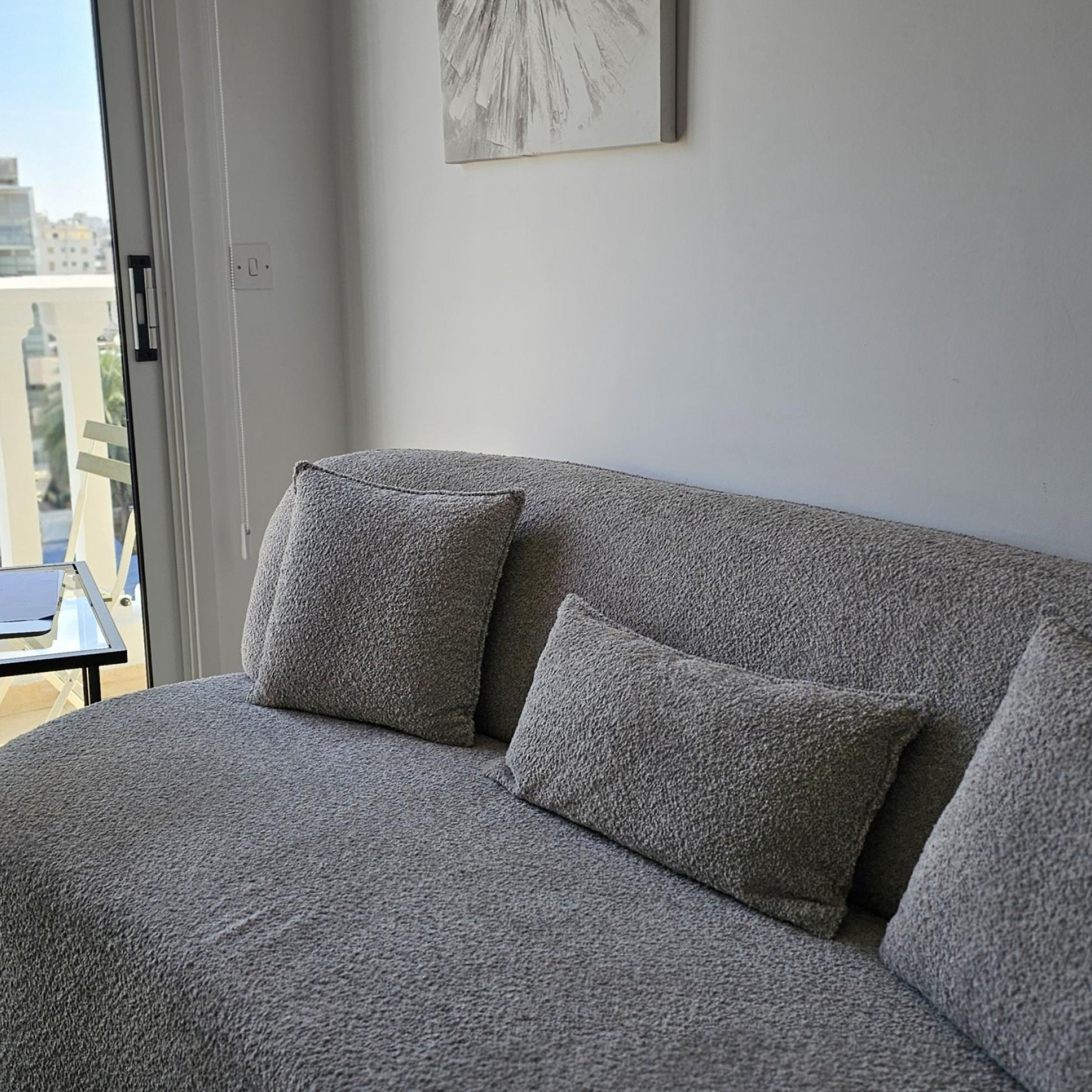 A grey sofa with two cushions in a room with a large window.