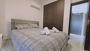 Un dormitorio con cama, armario, aire acondicionado y una puerta.