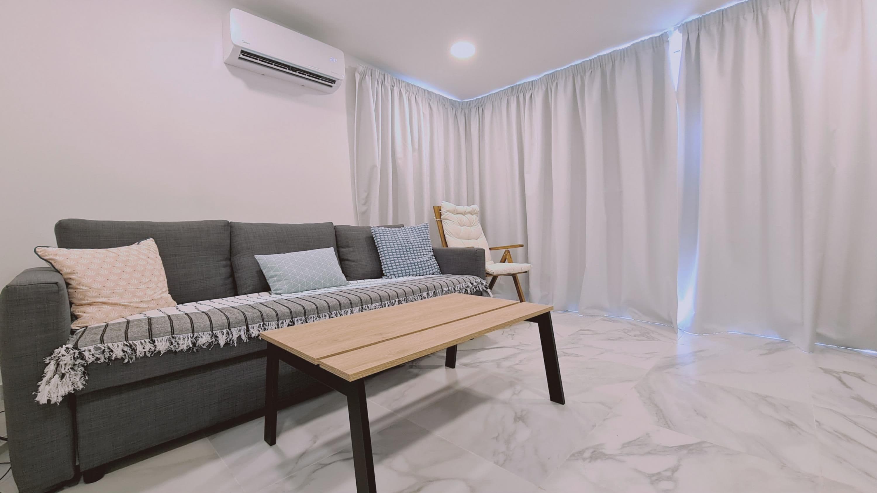 A modern living room with a grey sofa, a wooden coffee table, and a chair.