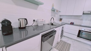 Een moderne keuken met een vaatwasser, oven en koffiezetapparaat op het aanrecht.