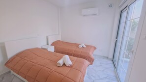 A hotel room with two beds, white nightstands, an air conditioning unit, and a large window offering a view. - 88 PYL - Stay The Getaway (Pyla)