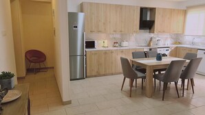 Une cuisine moderne avec des meubles en bois, un réfrigérateur en acier inoxydable, un four à micro-ondes et un coin repas comprenant une table et des chaises.