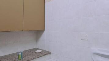 Un baño con un mueble color beige, una encimera de granito, un inodoro blanco y una pared con azulejos color beige.