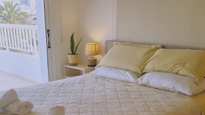 A neatly made bed with a quilted cover, two pillows, and two rolled towels on the side. - 83 Lim2 - Stay Naturaleza Penthouse (Limassol)