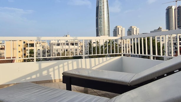 A rooftop terrace with lounge chairs and a view of modern high-rise buildings. - 83 Lim2 - Stay Naturaleza Penthouse (Limassol)