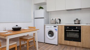 Een compacte keuken met een wasmachine, oven en een eethoek met tafel en stoelen.